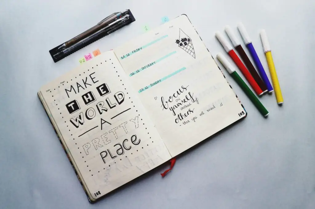 Open bullet journal with quotes and colorful markers for planning and creativity.