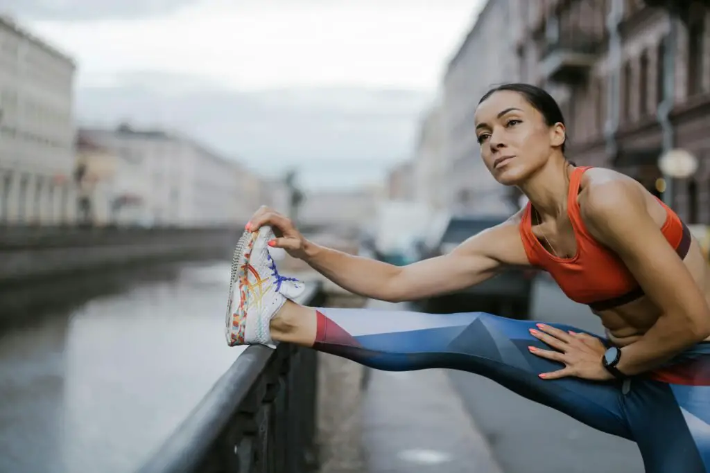 A fit woman in activewear stretches near a city canal, embodying urban fitness and wellness.